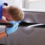 A pest control professional looks for bed bugs underneath a mattress