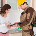 A woman signing a document handed to her by a male pest control worker